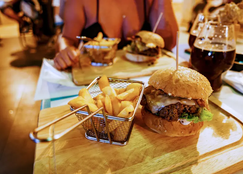 Burgare med pommes frites i en trådkorg på ett träbord