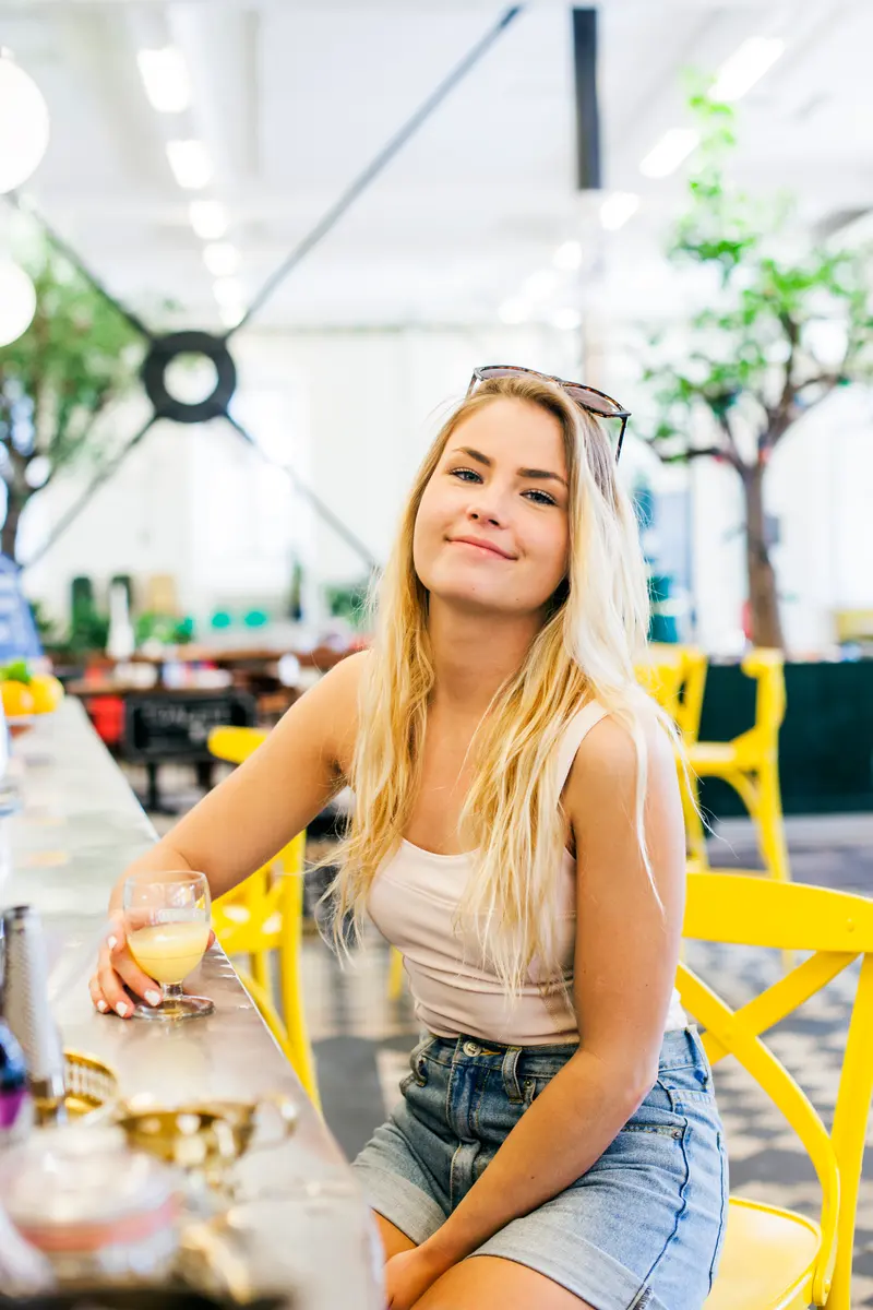 Gäst sitter vid baren med ett glas i handen i en ljus lokal