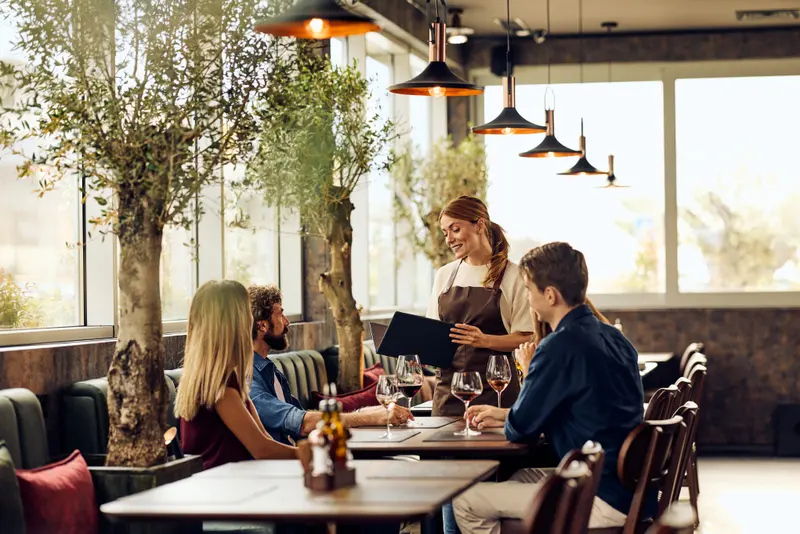 Servitris tar upp beställning från ett sällskap på en uteservering